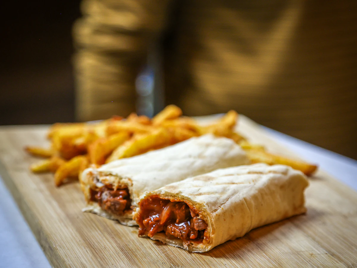 Dos kebabs enrollados con patatas fritas sobre una tabla de madera